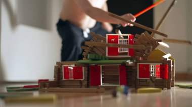 Ev yapımı minyatürü yok eden çocuk. Çocuk ahşap model evi tekmeliyor. Küçük çocuk yaramazlık, eğitici çocukluk konsepti