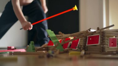 Ev yapımı minyatürü yok eden çocuk. Çocuk ahşap model evi tekmeliyor. Küçük çocuk yaramazlık, eğitici çocukluk konsepti
