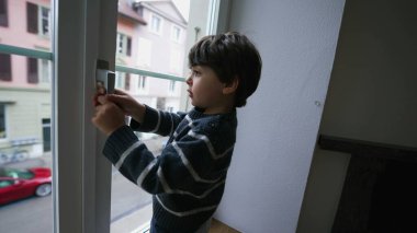 İkinci katın kapı kolunu tutan küçük bir çocuk. Çocuk güvenliği kavramı.