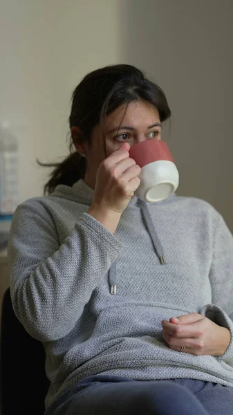 Woman sipping tea or coffee in vertical video. Person drinks hot beverage