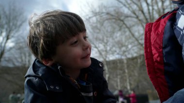 Çocuk sonbahar ya da sonbahar sezonunda atlıkarınca parkında eğleniyor. Yakın plan beyaz erkek çocuk kavşağın etrafında dönüyor mutluluk ve heyecan hissediyor.