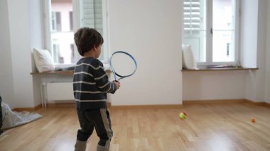 Yükselen Tenis Yıldızı / Çocuk Tenis Oyunları boş bir apartman dairesinde, aile yeni evine taşınıyor. Küçük çocuk duvara raketle vurarak egzersiz yapıyor.