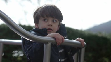 Çocuk, sonbahar sezonunda atlıkarınca bahçesinde hareket halinde. Küçük çocuk soğuk mevsimde parkın tadını çıkarıyor.