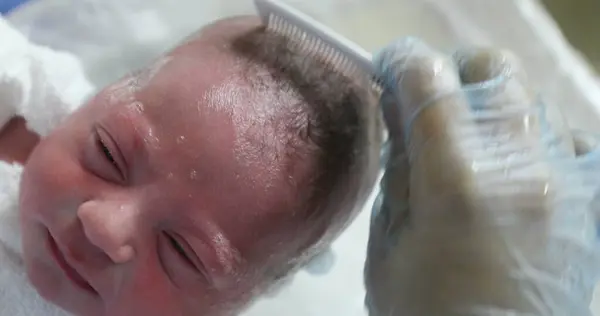 Combing newborn baby at hospital after birth