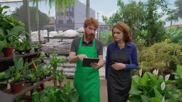 Colaboradores Redhair Utilizando Tablet Para Mostrar Inventário Loja Local Planta — Vídeo de Stock