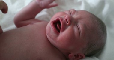 Crying newborn baby at hospital, first hours of life