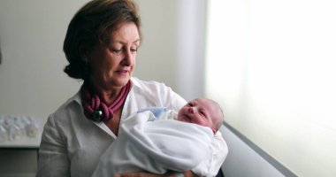 Grand-mother holding newborn baby infant grand-son
