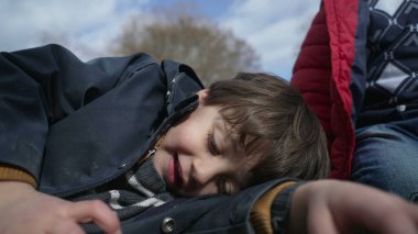 Sonbahar sezonunda okul bahçesindeki kavşağa yakın duran çocuğun yüzü, açık havada güneşli bir günde ceketini giyen çocuğun yüzü.