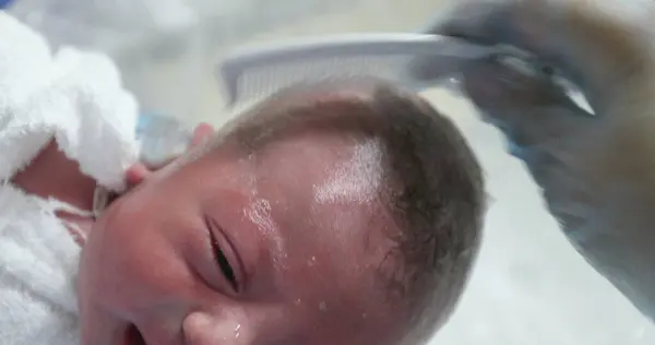 Combing newborn baby at hospital after birth