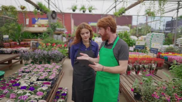 Чоловічий Персонал Обмінюється Інвентаризаційними Даними Планшеті Жіночою Колегою Квітковому Магазині — стокове відео
