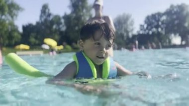 Yaz Eğlencesi - Çocuk Güneşli bir günde Yüzer ve Su Eriştesi ile Havuzda Dinlenmiş ve Güvenli Kalır