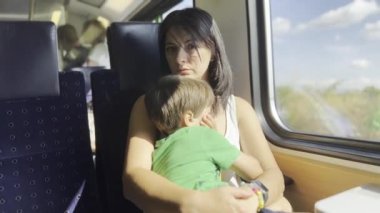 Bir tren yolculuğunda yorgun anne ve oğlu, güneş ışığı oğlanın uykulu yüzünü pencereden gıcık ediyor.