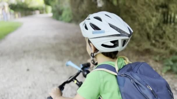 住宅ライド セリーンストリート 遊び場の景色にヘルメットとバックパックバイクの子供 — ストック動画