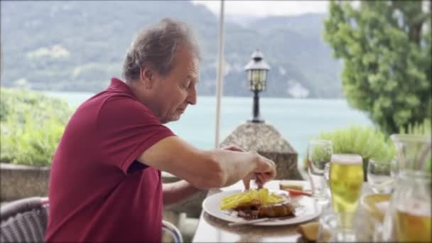 Alpine Delight Senior Man Gosta Salsicha Suíça Batatas Fritas Cerveja — Vídeo de Stock