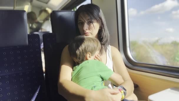 電車の旅で疲れたママと息子 サンライトは窓から男の子の眠い顔をノイズする — ストック動画