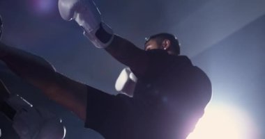 Muay Thai dövüşçüsü, 800 fps hız rampası ve dramatik ışıklandırma ile rakibini ultra yavaş çekimde yeniyor. Adam rakibi tekmeliyor