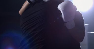 Boks eldiveni giyen iki boksör savunma taktiği sırasında birbirlerini sıkıca kavrıyorlar. Rakipler yumrukları önlemek için birbirlerine sarılıyorlar.