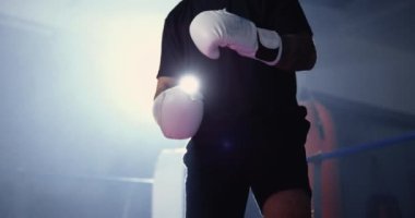 Boksör iç ringde boks eldivenleri giyiyor dramatik ışıklandırmada beklemede.