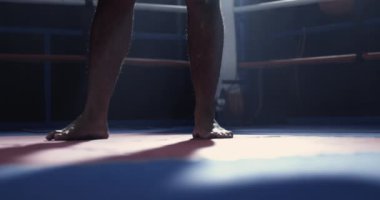 Boks ringinde duran erkek bacakları, çarpıcı ışıklandırması olan kişiye yakın çekim.