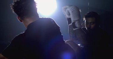 Adam rakibine ağır çekimde hız rampasıyla vuruyor. İki Muay Thai dövüşçüsünün rekabete girdiği dramatik bir sahne.