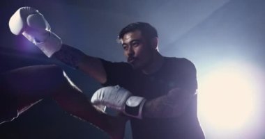 Dövüşçü ringin içinde bacak vuruşu yapıyor. Boks eldiveni giyen adam Muay Thai antrenmanı yapıyor.