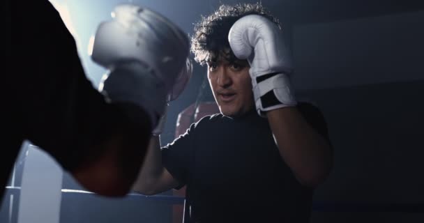 フォーカスデュエル ボクシンググローブのヤングマン 反対者との強烈なガイズロック 劇的にライトスローモーションリングシーン — ストック動画