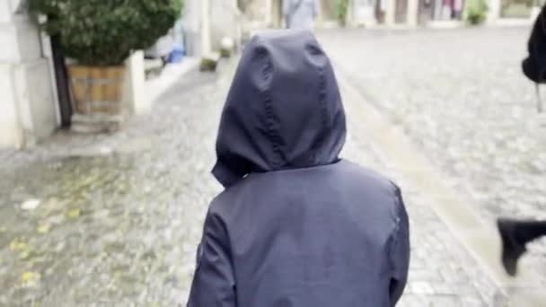 雨城漫步 多云天气下的小巷小径上的头戴头罩的男孩 — 图库视频影像