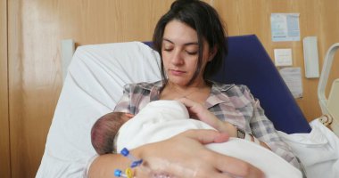 Mother breastfeeding newborn baby at hospital after birth