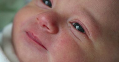 Newborn baby boy looking and observing the world, first day of life