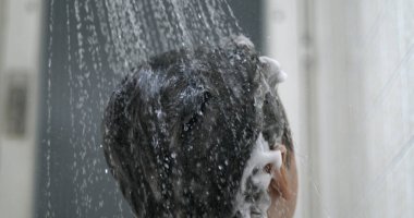 Çocukların saçlarına akan su çok yavaş çekimde yıkama şampuanı, banyo rutini. Çocuğun kafasını duş başlığıyla yıkamak.