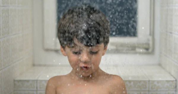 Young boy looking at droplets fall in super slow-motion during bath time. shower head water falling down