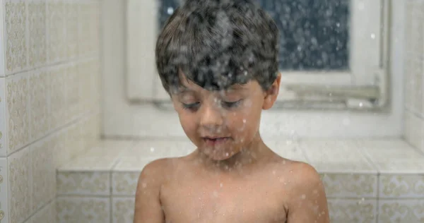 Young boy looking at droplets fall in super slow-motion during bath time. shower head water falling down