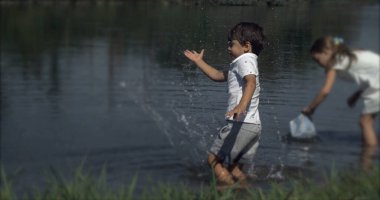 Çocuk Elle Sıçratan Göl Suyu Ultra Yavaş Çekimde. Genç Çocuk Göl 'den Oynuyor, Doğayla Bağlanıyor