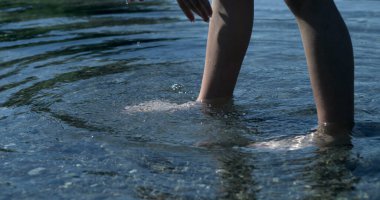 Su birikintisinin içinde dalgalanan çocuk bacakları, doğayla temasta olan insan.