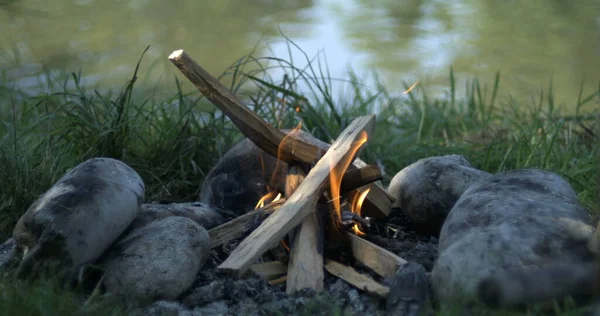 Small bond fire by lake captured with high-speed camera, flames and wood burning in camping day