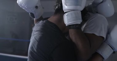 Dövüşçüler yumruk ve tekmeleri önlemek için birbirlerini sardılar. Boks ringinde iki adam.