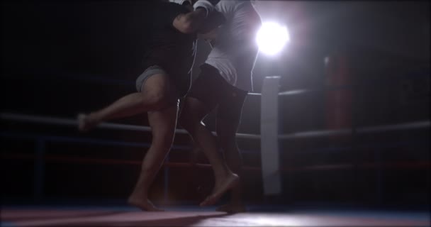 拳击手在拳击台内互相打斗 男子把膝盖踢向对手的身体 互相包扎以防止拳打脚踢 — 图库视频影像