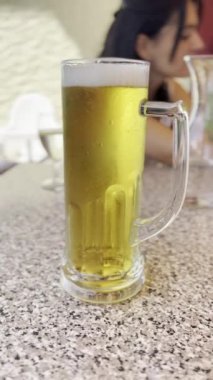 Serinletici Bira - Buzlu Bira Masanın Altında, Kabarcıklar Yükseliyor, Arkaplanda Kadın