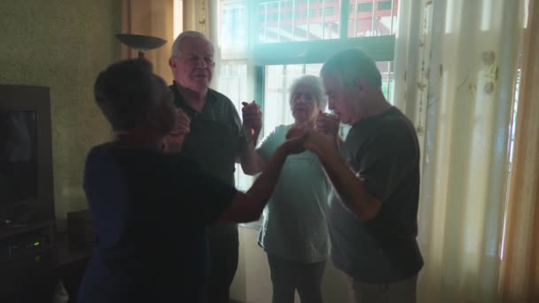 一群老年人一起在家里祈祷 阳光透过窗户照耀着他们 有四位敬业的长者手拉手祷告 希望能与家常便饭携手共进 — 图库视频影像