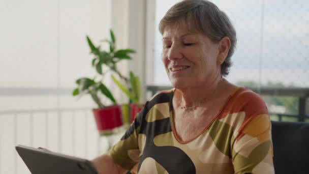 了解技术的老年妇女与公寓的餐桌订婚 与现代科技互动的快乐表达 — 图库视频影像