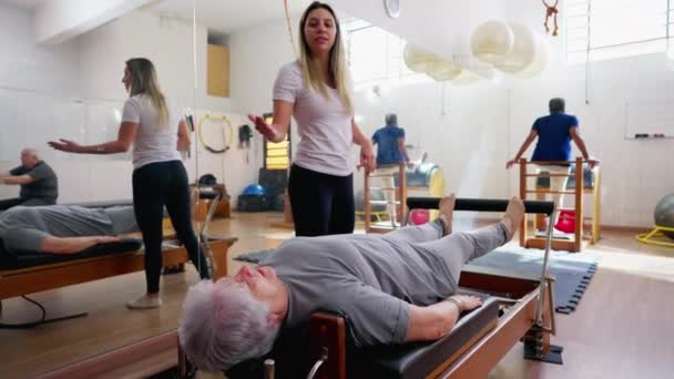 Pilates Instructor Guiding Senior Woman Machine Old Age Workout Routine — Stock Video