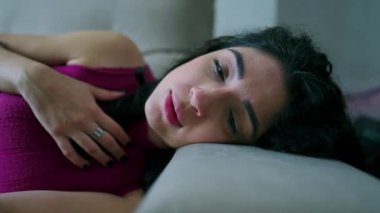 Depresyondaki kadın kanepede yatıyor. 30 'lu yaşlarda, duygusal sıkıntıdan muzdarip mutsuz yüzlü bir kadın.