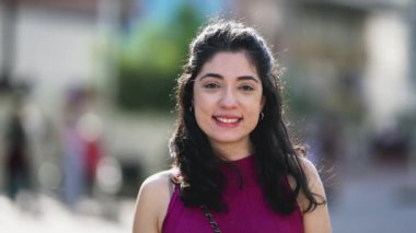 Güneşli bir günde dışarıda kameraya poz veren mutlu bir genç kadın. 30 'lu yaşlarda bir kadın portresi.