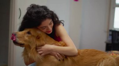 Kadın, evindeki sevgili Golden Retriever evcil hayvanıyla iç açıcı bir anı paylaşıyor. Sevgi sahibi köpek arkadaşını kucaklıyor.