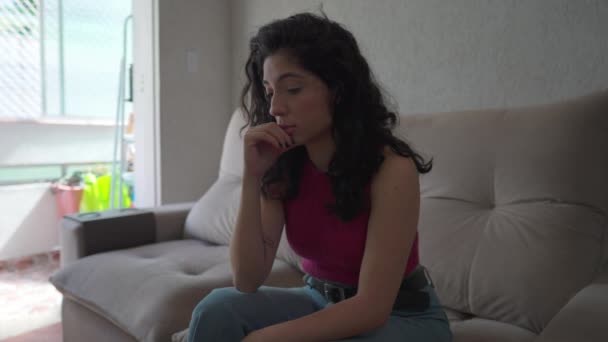 Μια Σκεπτική Νεαρή Γυναίκα Κάθεται Στον Καναπέ Στο Σπίτι Στοχαστική — Αρχείο Βίντεο