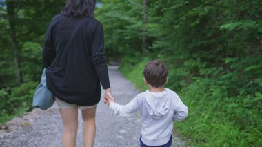 Anne ve Çocuk Doğa Yolu 'nda el ele yürüyorlar, Hafta sonu yürüyüşünün tadını çıkarıyorlar. Maceraperest aile açık havada, yolculuk yolu konseptinin tadını çıkarıyor.