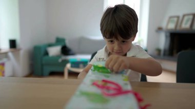 Heyecanlı Çocuk 'un açılış hediyesi. Küçük bir çocuk hediyeyi açıyor, yırtık bir kağıt parçası, ödül için sabırsızlanıyor.