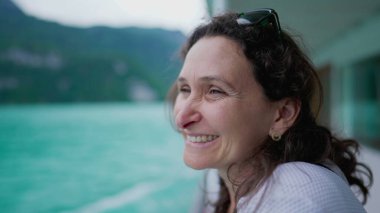 Mutlu kadın göl ve dağ manzarasını gözlemlemek için tekneyle seyahat ediyor, tatillerin tadını çıkarıyor, 40 'lı yaşlarda neşeli, dingin ve huzurlu bir kadın yüzü var.