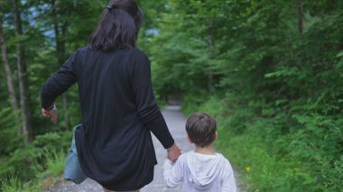 Anne ve Çocuk Doğa Yolu 'nda el ele yürüyorlar, Hafta sonu yürüyüşünün tadını çıkarıyorlar. Maceraperest aile açık havada, yolculuk yolu konseptinin tadını çıkarıyor.