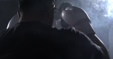 Çarpıcı ışıklandırma bakışlarıyla iç halkalara bakan iki dövüşçü. Boks eldiveni giyen dövüşçü rakibinin karşısına yavaş çekimde 800 fp ile çıkıyor.